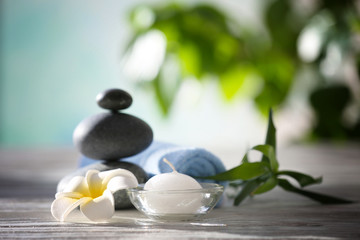 Spa stones with towel, tropical flower, bamboo and candle on blurred background