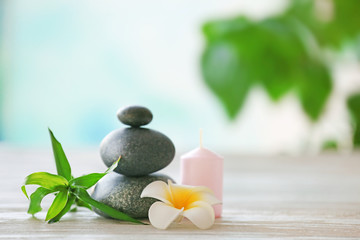 Spa stones with candle, bamboo and tropical flower on blurred background