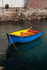 Fototapeta na wymiar Blue and yellow rowing boat in a harbour