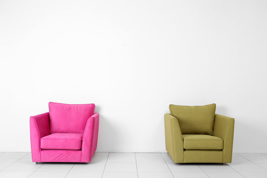 Living room interior with pink and green armchairs on white wall background