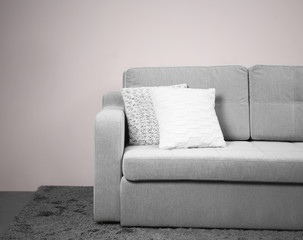 Fototapeta na wymiar Grey comfortable sofa against white wall in the room