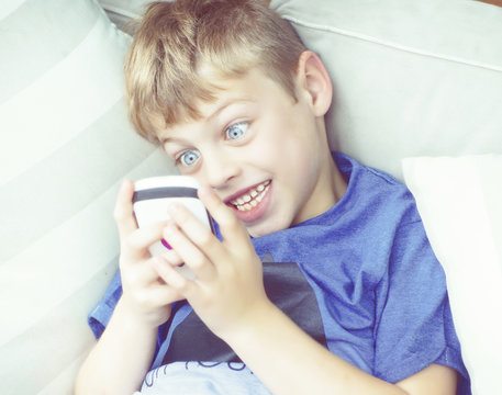 blonde boy playing phone at home