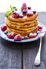 Pancakes with honey and berries on white background