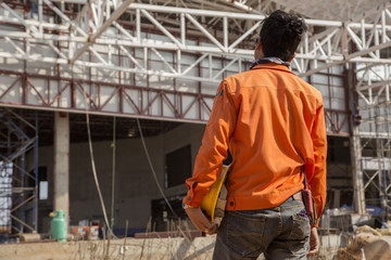 Naklejka na ściany i meble worker standing in site and steel frame background