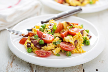 Scrambled eggs with peas, bacon and tomatoes