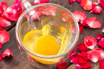 Egg in heart cup and rose on wooden