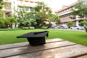 Graduation hat on vintage table with green nature background