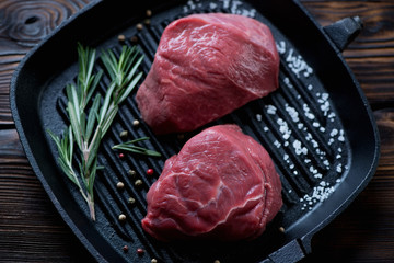 Uncooked fillet mignon beefsteaks on a cast-iron grill, close-up