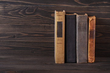 group of old hardcover books on a dark wooden background