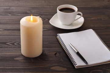 open notebook with blank pages, pen, coffee, burning candle