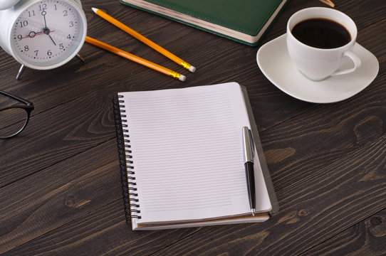 Open notepad with blank pages on a dark office desk