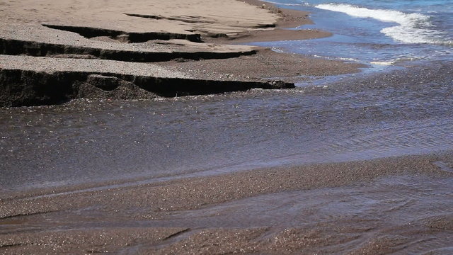 River flows on black volcanic to sand.