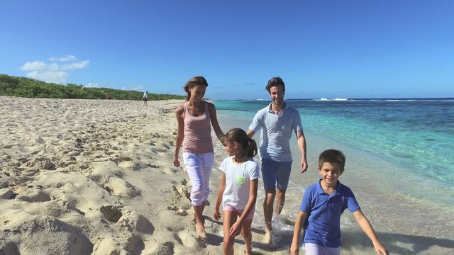 Family of four walking on a sandy caribbean beach