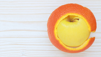 Pomme et pelure d'orange sur fond bois blanc
