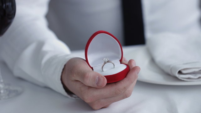Close up Man holding box with ring making propose to his girlfriend, restaurant 