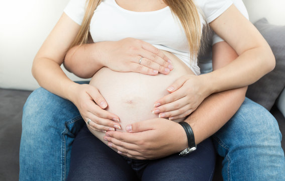pregnant couple holding hands on big belly