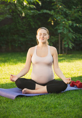 Beautiful pregnant woman relaxing and meditating outdoors