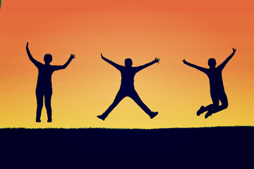 The silhouette of three people jumping with orange background,concept of happiness, joy, joyful life