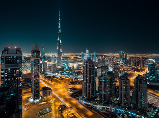 Fantastic rooftop view of Dubai's modern architecture by night with illuminated skyscrapers.