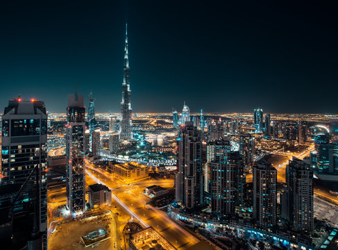 Fantastic rooftop view of Dubai's modern architecture by night with illuminated skyscrapers. © Funny Studio