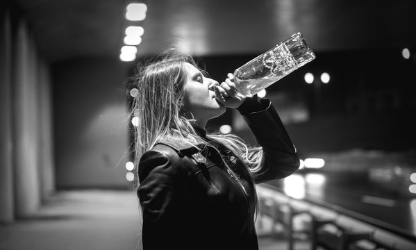 black and white portrait of woman drinking whiskey at night on s