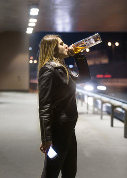 Portrait of woman drinking whiskey from bottle and night