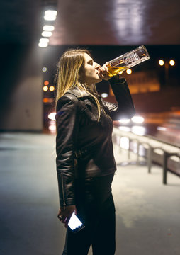 lonely woman drinking alcohol from bottle at highway