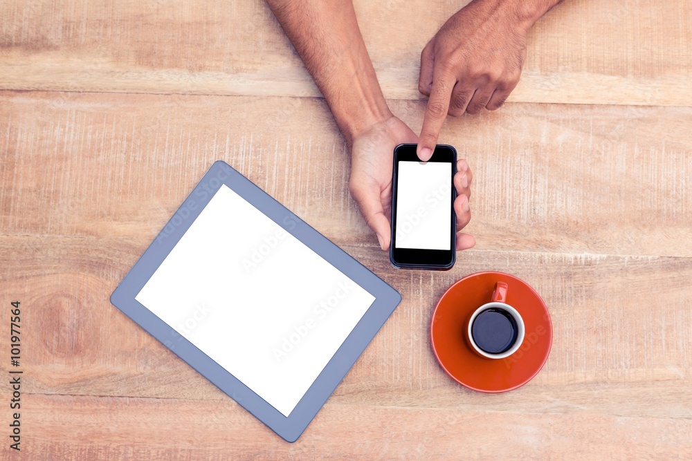 Poster person using smart phone by coffee and tablet on table