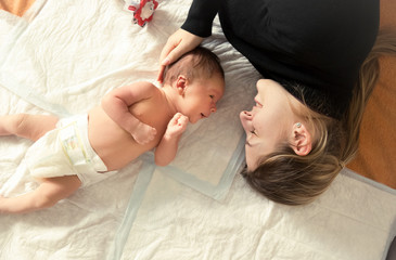 Toned portrait of mother lying with her newborn on bed