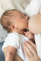 Obraz na płótnie Canvas Closeup of newborn baby boy eating mothers breast milk