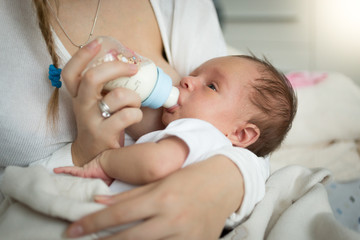 Closeup of mother feeding newborn baby from bottle