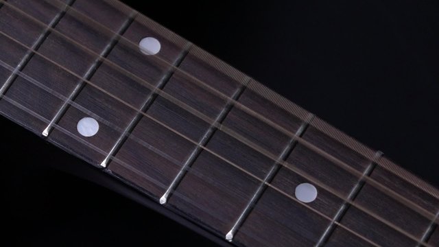 Strings of acoustic guitar, on black, close up, slow motion