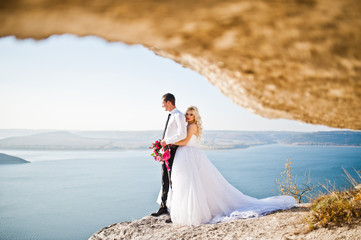 Fototapeta na wymiar Charming bride and elegant groom on landscapes of mountains, wat