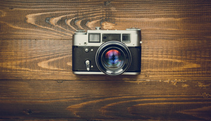 Toned image of old camera with manual lens on wooden background