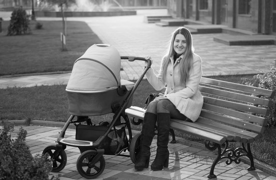Black and white photo of mother sitting on bench with baby strol