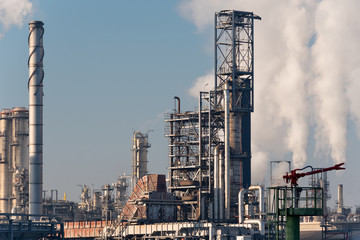 Fototapeta na wymiar smoking chimneys of an oil refinery against blue sky