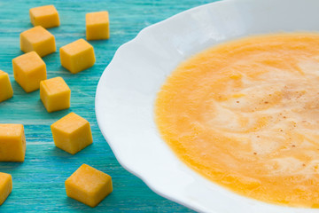 Pumpkin soup with sour cream and seeds on a wooden turquoise table. Selective focus, Still life, food and drink concept.