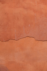 Obraz premium Old terracotta painted stucco wall with cracked plaster. Backgro