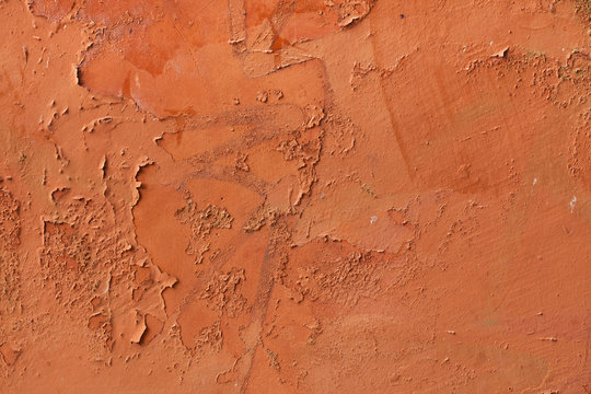 Old terracotta painted stucco wall with chipped paint. Backgroun