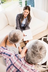 Smiling businesswoman showing documents to senior couple