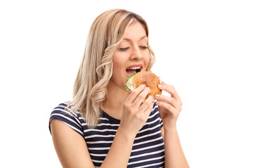 Joyful young woman eating a sandwich