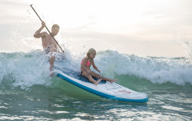 Father and daughter making paddlesurfing