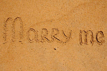 Marry Me Word Written On Sunny Beach Sand with ring
