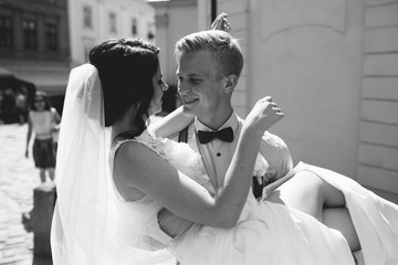 groom carries bride in his arms