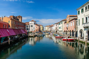 View over channel witn boats, houses and reflections in Chioggia