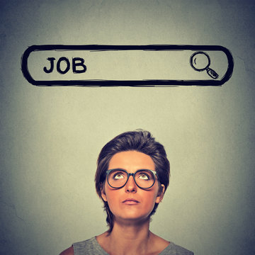 Headshot young woman in glasses thinking looking for a new job isolated on gray wall background