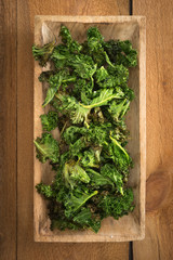 Kale chips with sea salt in a brown bowl on a wooden table