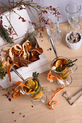 Two Glasses of hot mulled wine with orange slices, cinnamon, thyme on wooden table. Warming drink with ingredients.