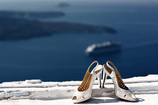 Elegant white wedding shoes on roof with sea in background in Sa