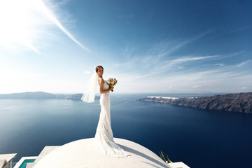 Romantic beautiful bride in white dress posing on terrace with s